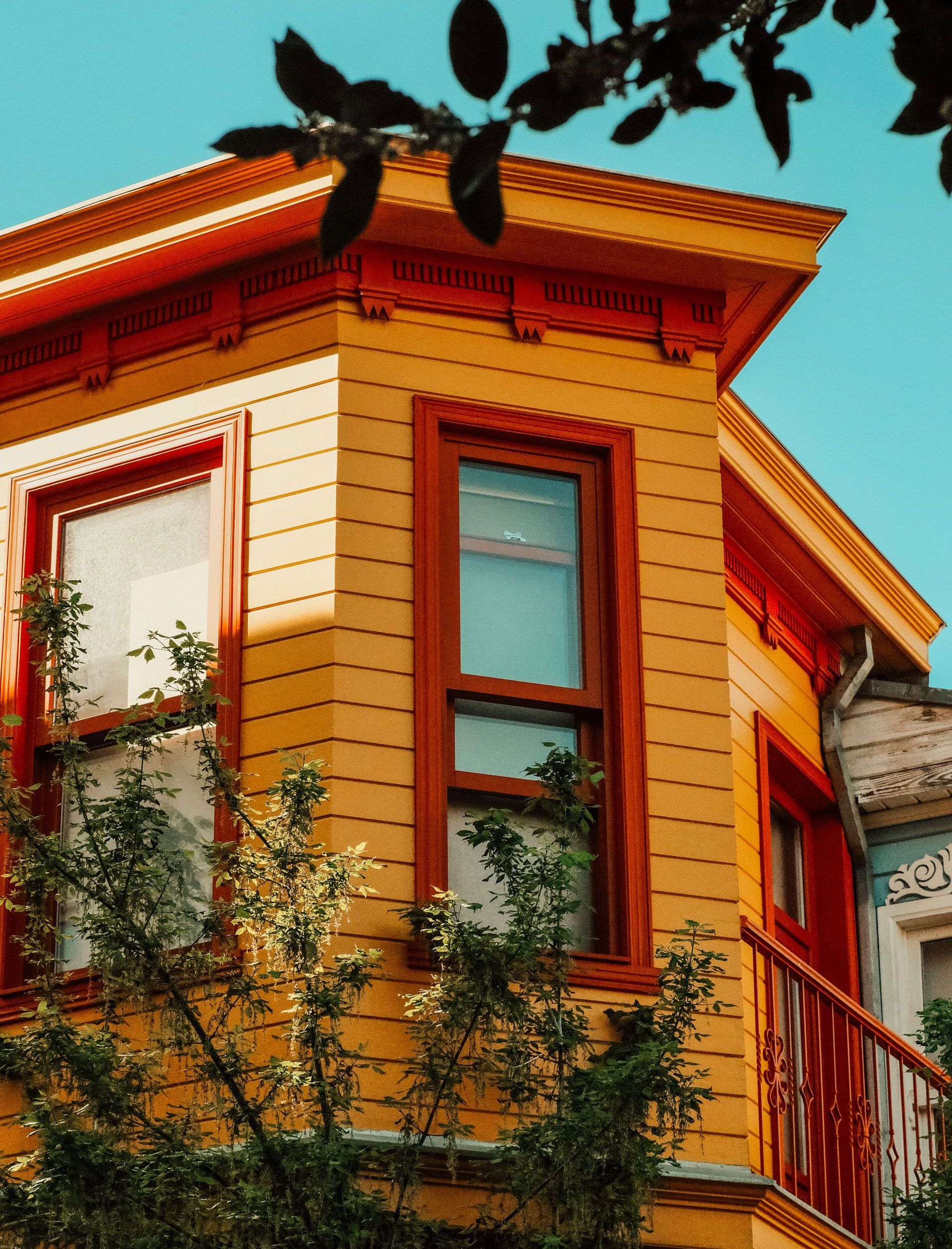 Colorful residential building facade with vibrant yellow paint and balcony, set against a clear sky in İstanbul.